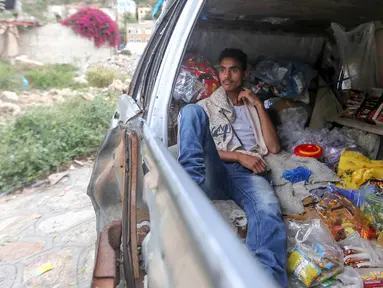 Majd al-Din al-Shamiri (16) menunggu pembeli di toko darurat di kawasan Jabal Sabr, Yaman pada 28 September 2019. Majd al-Din al-Shamiri mengubah mobil keluarganya yang rusak parah, akibat perang yang melanda, menjadi toko darurat untuk membantu keluarganya mencari nafkah. (Ahmad AL-BASHA/AFP)