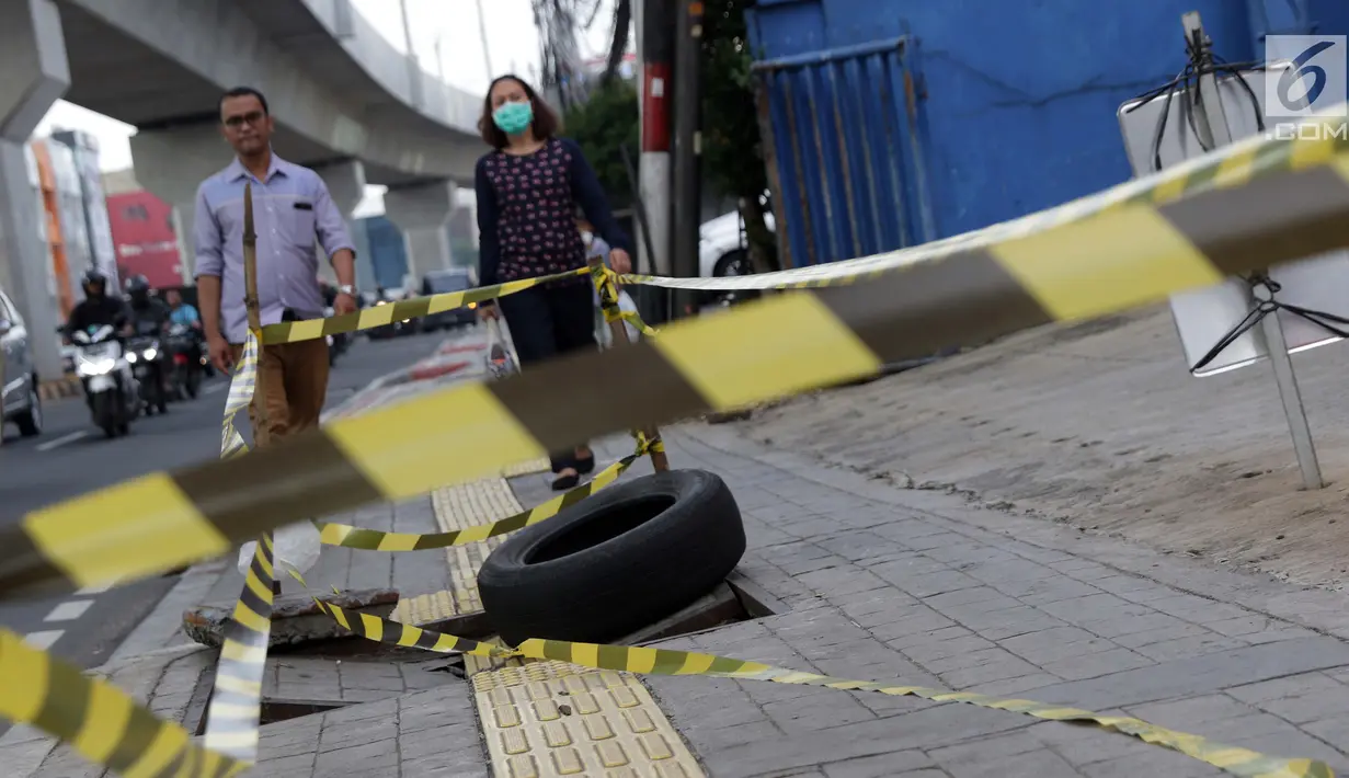 Pejalan kaki melintas di dekat penutup trotoar yang rusak di Jalan RS Fatmawati, Jakarta, Selasa (14/7/2019). Dua buah penutup trotoar di Jalan RS Fatmawati rusak parah, kondisi ini mengganggu kenyamanan dan membahayakan pejalan kaki, terutama pada malam hari. (Liputan6.com/Helmi Fithriansyah)