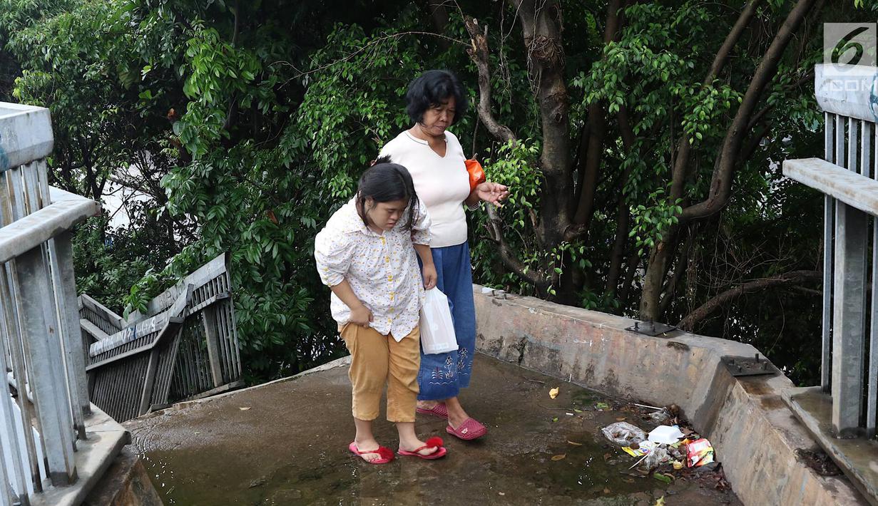 Pejalan kaki melintasi JPO yang rusak di Terminal Kampung Rambutan, Jakarta, Senin (28/1). Kondisi JPO yang sebagian pagar pembatasnya rusak tersebut membahayakan pejalan kaki apabila tidak segera diperbaiki. (Liputan6.com/Immanuel Antonius)