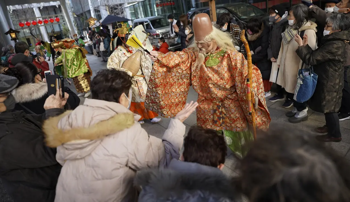 Seniman yang menggambarkan Tujuh Dewa Keberuntungan Jepang, bersama para pengunjung, berdoa selama Festival Konpira di kuil Kotohiragu di distrik bisnis Toranomon, Tokyo, Selasa (10/1/2023). Kehadiran para seniman dalam Festival Konpira pertama di tahun 2023 itu sukses menarik perhatian masyarakat.  (AP Photo/Eugene Hoshiko)