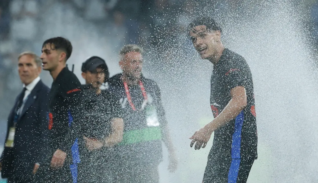 Pemain Barcelona, Hector Fort, menikmati siraman air dari lapangan usai mengunci gelar juara LaLiga 2024/2025 setelah mengalahkan Espanyol pada pertandingan ke-36 di RCDE Stadium, Jumat dini hari WIB (16/5/2025). (AP Photo/Joan Monfort)