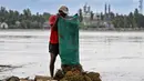 Banjir bandang yang menerjang wilayah Meureudu, Kabupaten Pidie Jaya, Provinsi Aceh merendam ribuan hektare sawah dan lahan pertanian. Tampak dalam foto, seorang petani mengeringkan padi di samping sawah yang terendam lumpur setelah banjir bandang di Meureudu, Kabupaten Pidie Jaya, Provinsi Aceh, pada Senin 8 Desember 2025. (Chaideer MAHYUDDIN/AFP)