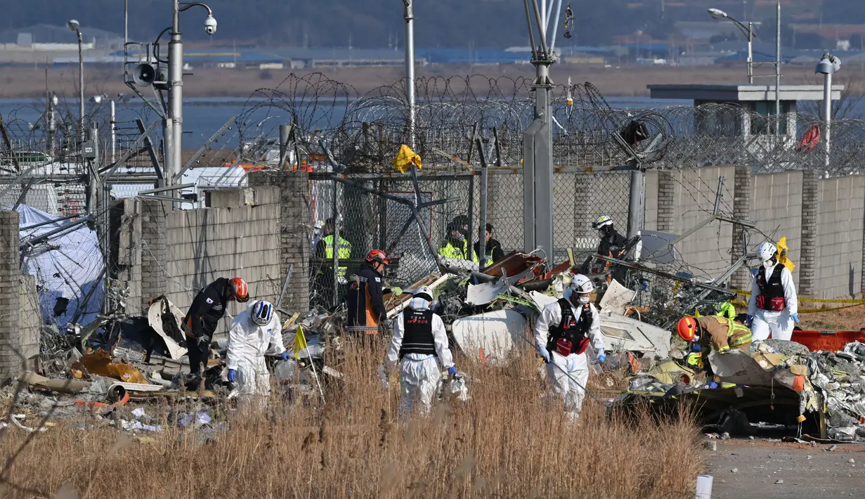 Petugas penyelamat terus berupaya mengevakuasi penumpang dari bagian belakang jet. (JUNG YEON-JE/AFP)