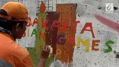 Para petugas PPSU ditugaskan melukis  mural di tembok kali Mookervart untuk menyambut  Asian Games.