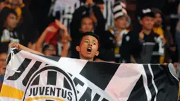Sambil membentangkan bendera, salah satu suporter Juventus bernyanyi merayakan kemenangan I Bianconeri atas ISL All Stars 8-1 di Stadion GBK, Jakarta, (6/8/2014). (Liputan6.com/Helmi Fithriansyah)