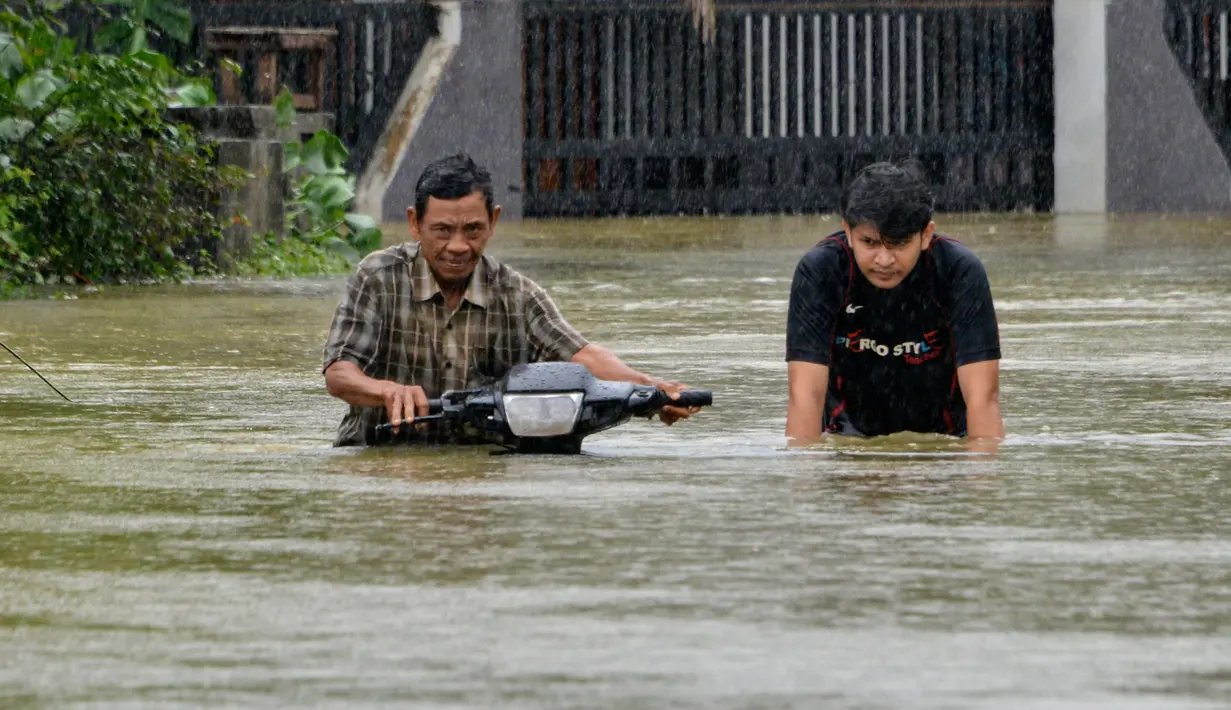 Warga mendorong sepeda motornya menerebos banjir setelah tiga hari diguyur hujan lebat di Banda Aceh, Aceh, Sabtu (9/5/2020). Banjir akibat intensitas hujan tinggi tersebut mengakibatkan sebagian besar kawasan di ibu kota Provinsi Aceh ini digenangi air. (Photo by CHAIDEER MAHYUDDIN/AFP)