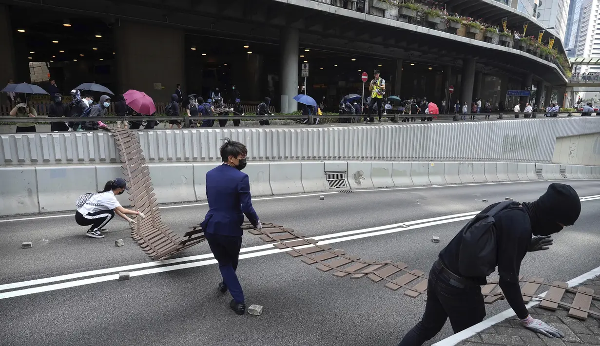 Demonstran menyeret pagar untuk menghalangi jalan selama protes di distrik keuangan di Hong Kong (14/11/2019). Warga Hong Kong mengalami hari keempat kemacetan lalu lintas dan gangguan angkutan massal ketika pengunjuk rasa menutup beberapa jalan utama dan jaringan kereta api.  (AP Photo/Vincent Yu)