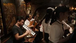 Dua musisi menghibur pengunjung di bar kecil di Golden Gai di distrik Shinjuku Tokyo (28/7/2019). Lebih dari 200 bar kecil bergaya klub dan restoran di area ini. (AP Photo / Jae C. Hong)