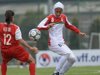 Pemain wanita Iran, Sabnam Behesht (kanan) berebut bola dengan pemain Singapura Ho Hui Xin selama kualifikasi Kejuaraan Piala Asia Wanita AFC tahun 2018 di Hanoi, Vietnam (5/4). (AFP Photo / Hoang Dinh Nam)