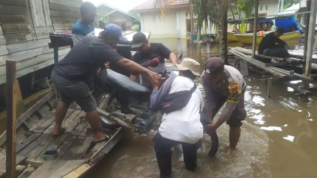 Personel Polsek Langgam jajaran Polres Pelalawan membantu warga yang menjadi korban banjir.