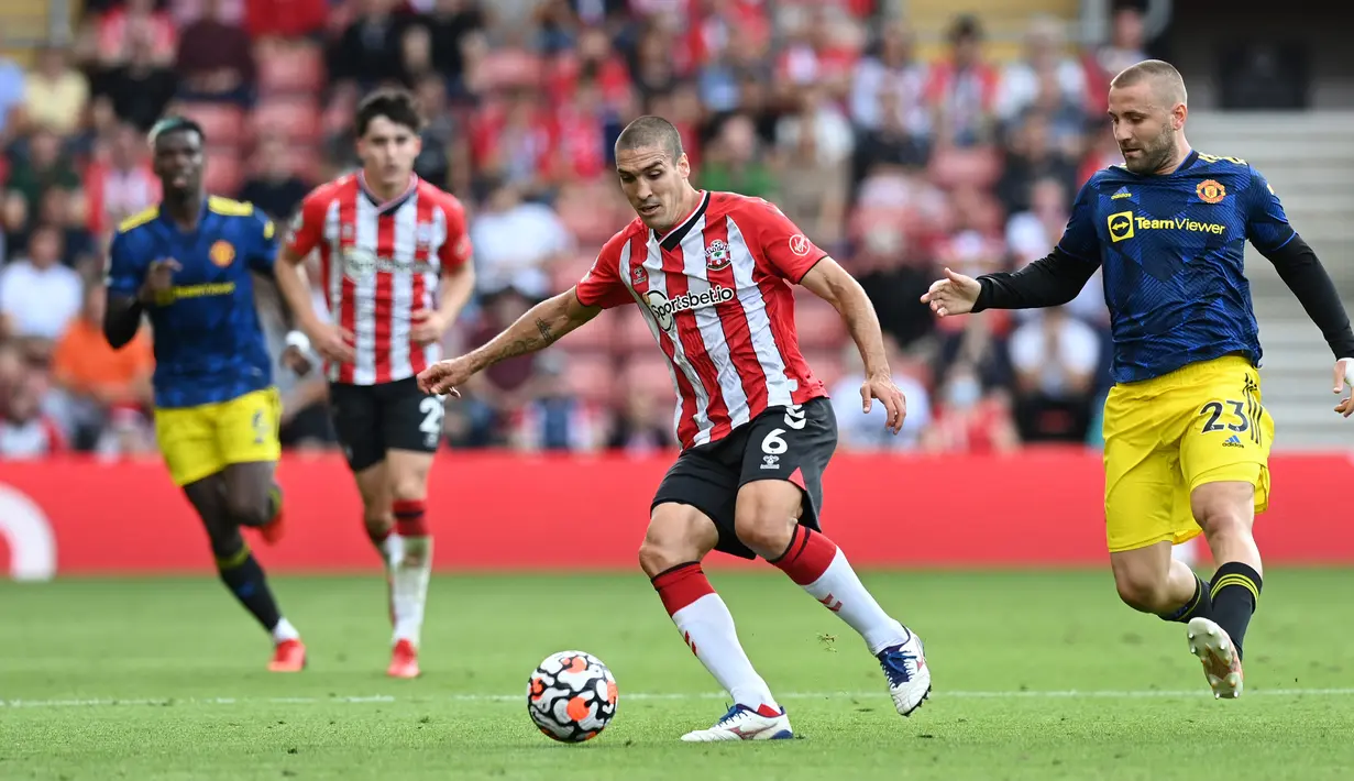 Pemain Southampton Oriol Romeu (tengah) mengontrol bola di depan bek Manchester United Luke Shaw (kanan) pada pertandingan Liga Inggris di Stadion St Mary, Southampton, Inggris, 22 Agustus 2021. Pertandingan berakhir imbang 1-1. (Glyn KIRK/AFP)