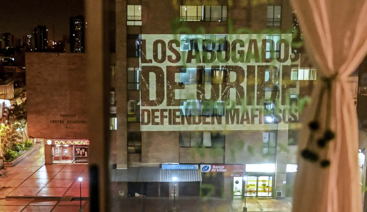 Slogan bertuliskan "Pengacara Uribe membela preman", mengacu pada mantan presiden Kolombia (2002-2010) Alvaro Uribe- diproyeksikan oleh aktivis @lanuevabandadelaterraza di bagian depan gedung, sebagai bagian dari cara baru untuk melakukan protes di Medellin, 9 Agustus 2020. (JOAQUIN SARMIENTO/AFP)