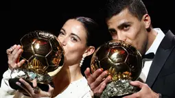 Pemain Barcelona, Aitana Bonmati (kiri) dan pemain Manchester City, Rodri mencium trofi Ballon d'Or pada acara yang berlangsung di Theatre du Chatelet, Paris, Selasa (29/10/2024) dini hari WIB. (AFP/Franck Fife)