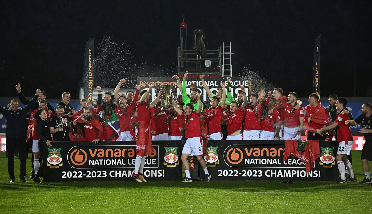 Sejumlah pemain, pelatih, dan official Wrexham merayakan kemenangan timnya saat laga English National League antara Wrexham melawan Boreham Wood di Racecourse Ground Stadium, Wrexham, Wales, Sabtu (22/04/2023). Wrexham menang dengan skor 3-1 dan berhasil promosi ke Liga Dua Inggris. (AFP/Oli Scarff)