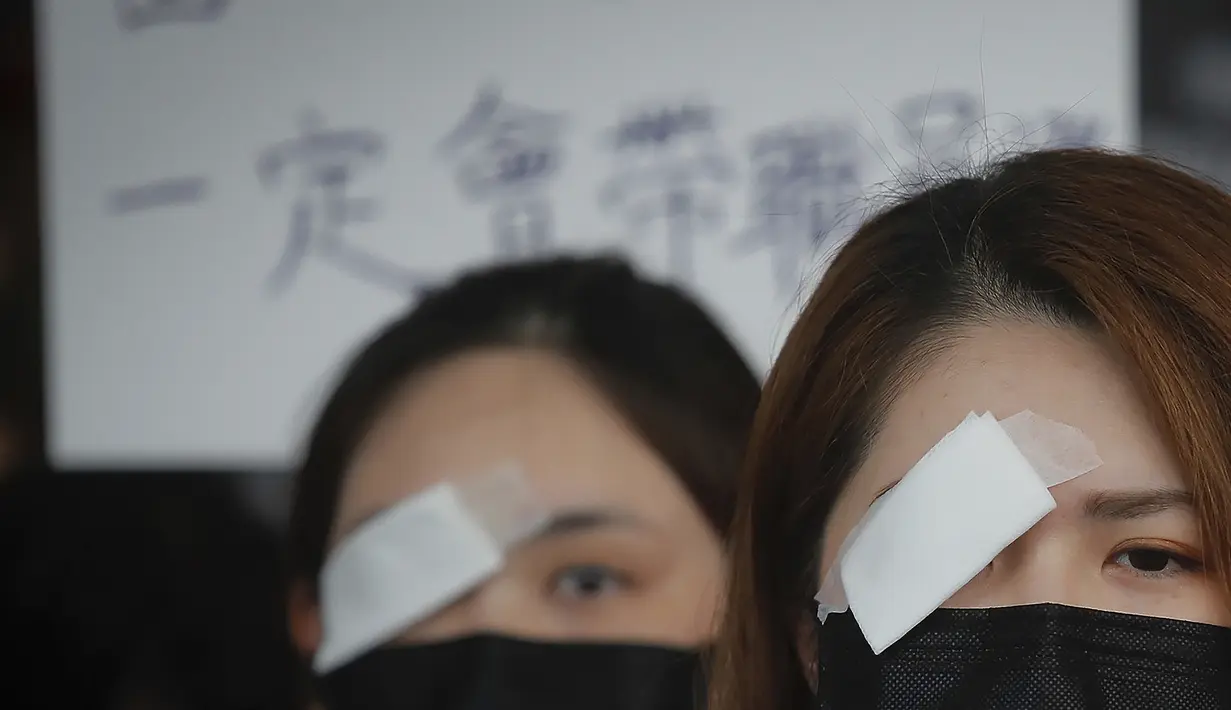 Seorang perawat mengenakan penutup mata dan masker mengambil bagian dalam protes terhadap kebrutalan polisi terhadap para pengunjuk rasa di sebuah rumah sakit di Hong Kong (13/8/2019). (AP Photo/Kin Cheung)