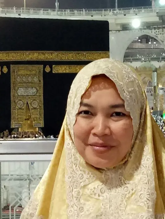 Bisa berfoto di depan Ka’bah wajah ibunda Ayu Ting Ting sangat berbahagia. Terlihat senyum semringah di wajah umi Kalsum yang memakai hijab berwarna kuning. (Instagram/mom_ayting92_)