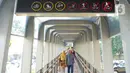 Pejalan kaki lewat di bawah rambu larangan untuk skuter listrik melintas yang terpasang di Jembatan Penyeberangan Orang (JPO) Bundaran Senayan, Jakarta, Jumat (15/11/2019). Rambu tersebut untuk mengantisipasi adanya penguna skuter listrik yang masuk ke JPO. (Liputan6.com/Immanuel Antonius)