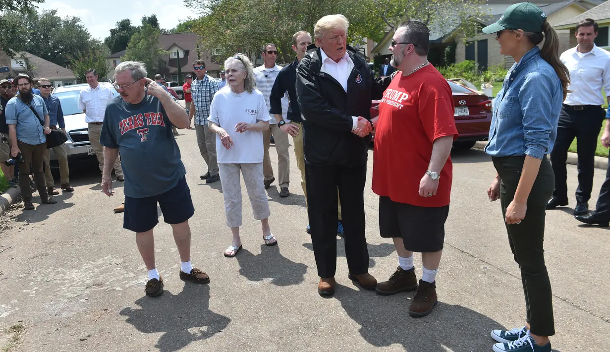 Presiden AS Donald Trump dan Ibu Negara Melania Trump menyapa warga sebuah lingkungan di Houston saat mengunjungi daerah-daerah yang terkena dampak Badai Harvey (2/9). (AFP Photo/Nicholas Kamm)