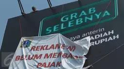 Petugas memasang spanduk bertuliskan "Reklame Ini Belum Bayar Pajak" di Kawasan Kebayoran Lama, Jakarta, Kamis (23/2). Razia oleh Satpol PP dan Dinas BP2T tersebut menertibkan reklame yang tidak membayar pajak. (Liputan6.com/Gempur M Surya)