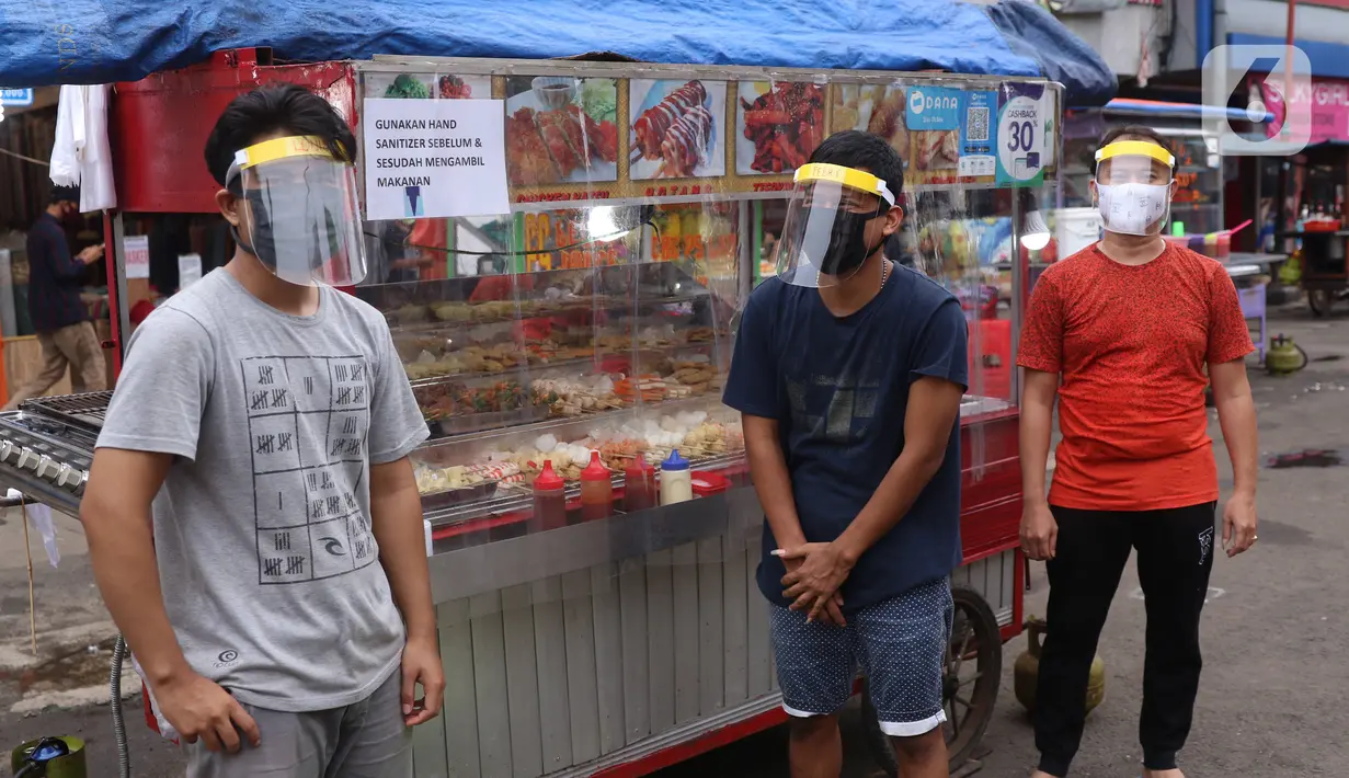 Pedagang mengenakan face sheild atau pelindung wajah saat berjualan di Tangerang, Banten, Rabu (13/5/2020). Penggunaan pelindung wajah tersebut dilakukan untuk mencegah risiko penularan virus corona COVID-19 pada saat berdagang. (Liputan6.com/Angga Yuniar)