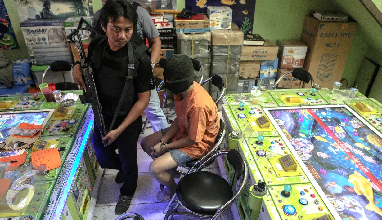 Petugas mengamankan seorang tersangka penyelenggara judi ikan di kawasan Penjagalan, Jakarta, Senin (3/8/2015). Dari tersangka petugas menemukan barang bukti berupa uang tunai Rp 5 Juta (Liputan6.com/Faizal Fanani)