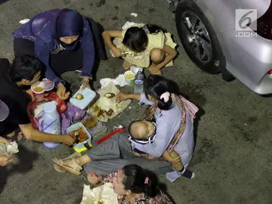 Pemudik makan bersama sambil menanti waktu masuk kapal di Dermaga II Pelabuhan Penyebrangan Merak, Banten, Senin (3/6/2019). Sambil menanti waktu bongkar muat kapal penyebrangan, pemudik memanfaatkan waktu untuk makan bersama. (Liputan6.com/Helmi Fithriansyah)