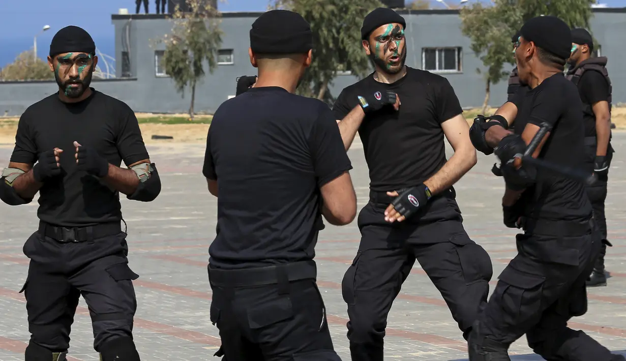 Anggota pasukan keamanan Hamas Palestina melukis wajah mereka saat menunjukkan keterampilan militer mereka saat upacara wisuda di Kota Gaza, Senin (21/2/2022). (AP Photo/Adel Hana)