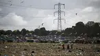 Penonton festival membawa barang-barang mereka saat berjalan melintasi lapangan yang dipenuhi sampah di akhir festival Glastonbury di desa Pilton di Somerset, barat daya Inggris, pada 26 Juni 2023. (AFP/Oli Scarff)