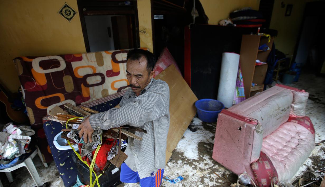 Warga lokal Alimin membersihkan puing-puing dari rumahnya setelah tsunami di Carita, Banten, Kamis, (27/12). Ratusan orang tewas akibat tsunami Selat Sunda akhir pekan lalu. (AP Photo/Achmad Ibrahim)