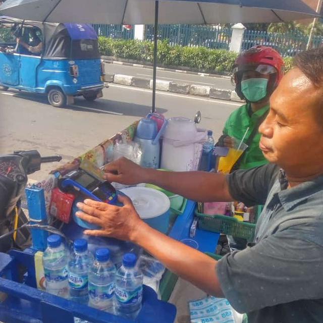 Aksi Penjual Minuman Layani Pembayaran dengan Mesin Debit