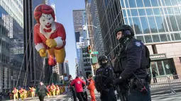 Polisi berjaga saat Balon Ronald McDonald memeriahkan parade Hari Thanksgiving di Manhattan, New York, AS (23/11). Peringatan 'Thanksgiving' merupakan Hari Pengucapan Syukur di akhir musim panen. (AP Photo/Mary Altaffer)