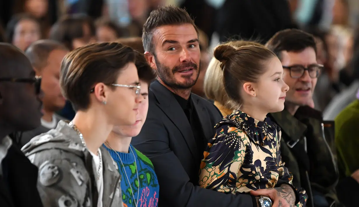 David Beckham bersama anak-anaknya Romeo Beckham, Cruz Beckham dan Harper saat menghadiri peragaan busana Musim Gugur/Musim Dingin 2020 Victoria Beckham dalam acara London Fashion Week di London, (16/2/2020). Beckham tampil dengan setelan jas hitam. (AFP/Daniel Leal-Olivas)