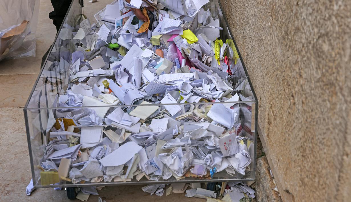Pekerja pemeliharaan di Tembok Barat, situs paling suci di mana orang Yahudi diizinkan untuk berdoa, melakukan pembersihan untuk menghilangkan dari celah-celah pesan agama dan doa yang tertulis di selembar kertas yang ditinggalkan oleh ribuan jemaah sebelumnya, di kota tua Yerusalem pada 20 September 2022. (AFP/Ahmad Gharabli)