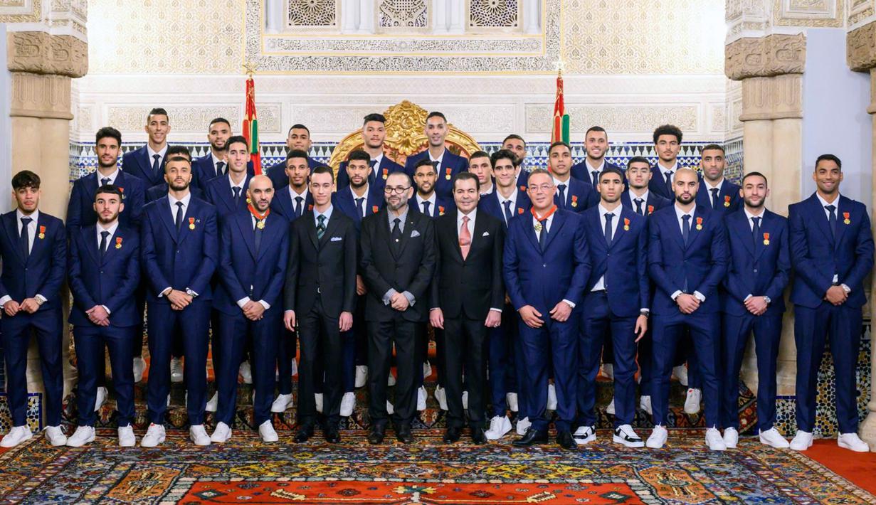 Raja Maroko Mohammed VI (tengah) diapit Putra Mahkota Maroko Moulay El Hassan (kiri) dan Pangeran Moulay Rachid (kanan) berpose bersama pemain Timnas Maroko di Istana, Rabat, Maroko, 20 Desember 2022. Timnas Maroko mendapat sambutan hangat di negaranya setelah berhasil meraih juara keempat Piala Dunia 2022. (Moroccan Royal Palace via AP)