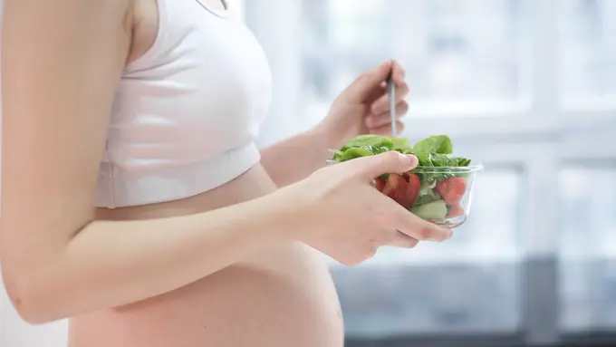 Seorang perempuan yang sedang hamil memegang semangkuk sayur-sayuran (Foto Dok: Freepik/onlyyouqj)