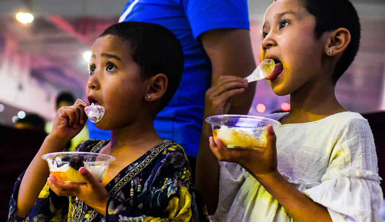 Anak-anak mencicipi makanan di sebuah pasar malam di Hotan, Daerah Otonom Uighur Xinjiang, China barat laut, pada 16 Mei 2020. Seiring cuaca mulai menghangat, aktivitas pariwisata lokal pun perlahan kembali pulih. (Xinhua/Wang Fei)