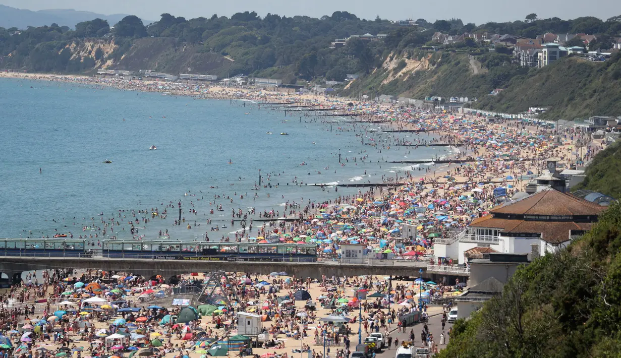 Kerumunan pengunjung berkumpul di pantai untuk menikmati hari terpanas tahun ini di Bournemouth, Kamis (25/6/2020). Para pejabat di Inggris selatan menyatakan keadaan darurat setelah ribuan orang berbondong-bondong menyambangi pantai setempat. (Andrew Matthews/PA via AP)