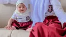 Terbaru, Ria Ricis mendandani baby Moana pakai seragam sekolah SD. Lengkap dengan hijabnya, baby Moana tampak begitu menggemaskan. Ria Ricis juga mengenakan baju yang sama dengan buah hatinya. (Liputan6.com/IG/@riaricis1795)