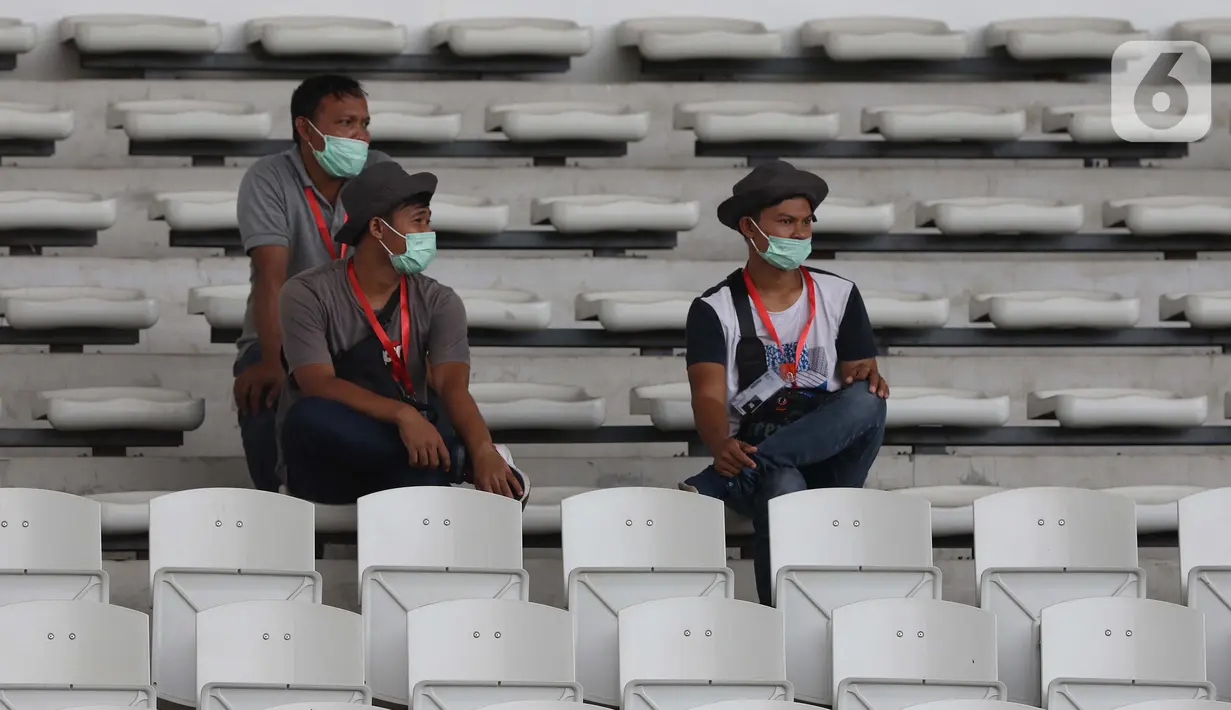 Pewarta mengenakan masker saat meliput laga kualifikasi Grup H Piala AFC 2020 antara PSM Makassar melawan Kaya FC-Iloilo, Jakarta, Selasa (10/3/2020). Pertandingan dilaksanakan tanpa dihadiri penonton sebagai antisipasi penyebaran virus Corona COVID 19. (Liputan6.com/Helmi Fithriansyah)