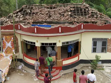 Warga berkumpul di sebuah kuil yang rusak akibat kebakaran di Kollam, India Selatan, Minggu (10/4). Media setempat melaporkan, kebakaran terjadi setelah perayaan yang menyalakan kembang api untuk menandai akhir sebuah festival. (REUTERS/Sivaram V)