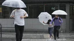 Orang-orang mengarungi genangan air saat mereka berjalan melintasi persimpangan di tengah hujan di Tokyo, Selasa (20/9/2022). Sebanyak dua orang dilaporkan tewas dan 100 orang lainnya akibat badai yang melumpuhkan lalu lintas, dan membuat ribuan rumah tanpa aliran listrik.  (AP Photo/Hiro Komae)