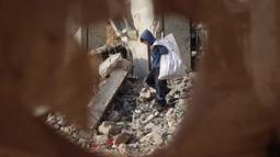 Perayaan Hari Anak Sedunia 2024 tidak bisa dirasakan oleh anak-anak yang berada di wilayah konflik. Tampak dalam foto, seorang anak laki-laki Palestina mengumpulkan barang-barang yang bisa diselamatkan dari puing-puing bangunan yang hancur akibat seragan Israel di Khan Yunis, Jalur Gaza selatan pada 19 November 2024. (Eyad BABA/AFP)