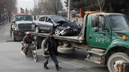 Pasukan keamanan Afghanistan memindahkan sebuah mobil yang hancur akibat terkena serangan bom bunuh diri di Kabul, Afghanistan (25/12). Bomber tersebut melancarkan serangannya saat para pekerja tiba di kantor mereka. (AP Photo / Rahmat Gul)