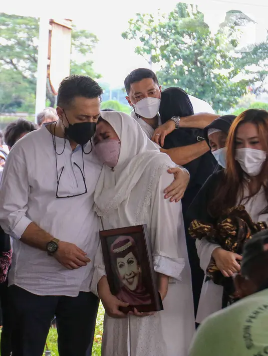 <p>Nia Zulkarnaen (kedua kiri), putri aktris senior Mieke Wijaya, menangis sambil memegang foto sang ibunda saat prosesi pemakaman di TPU Tanah Kusir, Jakarta, Rabu (4/5/2022). Mieke Wijaya meninggal dunia pada Selasa, 3 Mei 2022 di Jakarta. Ia meninggal dunia pada usia 82 tahun. (Liputan6.com/Herman Zakharia)</p>