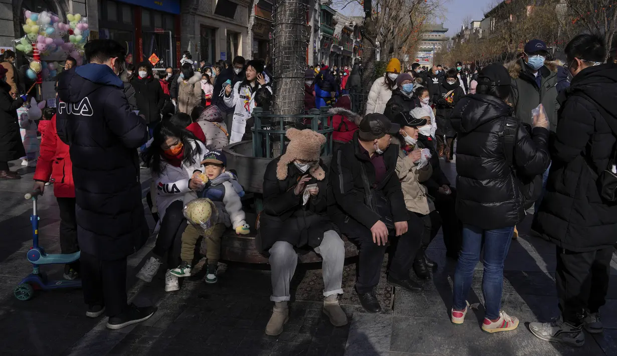 Pengunjung berkeliling shopping street pejalan kaki di Qianmen, tempat wisata populer pada hari pertama liburan Tahun Baru Imlek di Beijing, Minggu (22/1/2023). Orang-orang di seluruh China merayakan Tahun Baru Imlek pada hari Minggu dengan pertemuan keluarga besar dan kerumunan orang mengunjungi kuil-kuil setelah pemerintah mencabut kebijakan "nol-COVID" yang ketat, menandai perayaan meriah terbesar sejak pandemi dimulai tiga tahun lalu. (AP Photo/Andy Wong)
