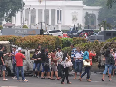 Sejumlah warga melihat mobil aparat yang dibakar demonstran 4 November di kawasan Monas, Jakarta, Sabtu (5/11). Pengunjung menjadikan dua kendaraan milik kepolisian tersebut sebagai objek foto dan melakukan swafoto. (Liputan6.com/Angga Yuniar)