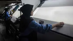 Lonjakan harga bahan baku didorong oleh kenaikan harga minyak mentah dunia, yang memengaruhi biaya bahan baku berbasis petrokimia (seperti polyester) dan biaya logistik. Situasi ini menyebabkan efek domino yang signifikan terhadap industri hilir, termasuk plastik dan kemasan, dengan kenaikan biaya produksi yang mencapai 90–100 persen. Tampak dalam foto, para pekerja memeriksa kain di Trisula Textile Industries, Cimahi, Jawa Barat pada Rabu 22 April 2026, saat para produsen tekstil menghadapi biaya yang lebih tinggi akibat melonjaknya harga bahan baku petrokimia yang terkait dengan kenaikan harga minyak global. (Timur MATAHARI/AFP)