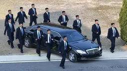 Pengawal berlari di samping mobil yang membawa Pemimpin Korea Utara Kim Jong-un saat akan menanam pinus dengan Presiden Korea Selatan Moon Jae-in dalam KTT Korsel-Korut di zona demiliterisasi, Panmunjom, Korsel, Jumat (27/4). (Korea Summit Press Pool/AP)