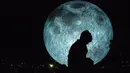 Pengunjung berjalan dekat replika bulan raksasa yang dipajang di Bratislava, Slovakia, 7 Oktober 2017. Replika bulan tersebut merupakan karya seniman Inggris, Luke Jerram yang bertajuk 'Museum of The Moon'. (JOE KLAMAR / AFP PHOTO)