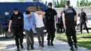 Polisi mengamankan dua dari 8 perwira militer pendukung kudeta Turki, di Alexandroupoli, utara Yunani, Minggu (17/7). 8 pria yang terbang dengan helikopter militer Turki itu ditahan petugas keamanan Yunani karena masuk secara ilegal (Sakis MITROLIDIS/AFP)